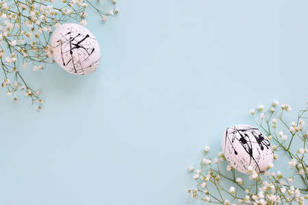 The two eggs are white in color with black spots and flowers on a blue background with a copy of the space. Easter. Minimalism. Festive background. Postcard. Frameの写真素材