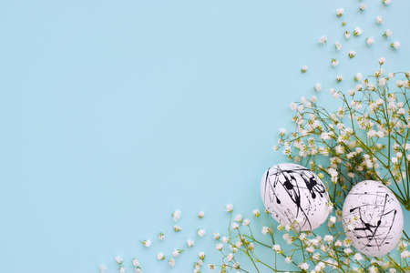 The two eggs are white in color with black spots and flowers on a blue background with a copy of the...