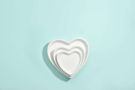 Three ceramic plates in the shape of a heart on a blue background, top view.の写真素材