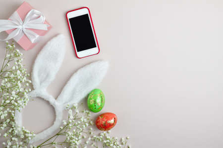 Easter background with rabbit ears and eggs, flowers and phone. Online greeting card.の写真素材