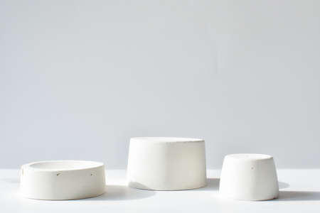 Three white catwalks with a geometric figure made of concrete. A scene with a cement display case....
