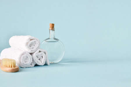 Glass bottles with towel and wooden body brush with natural bristles. Skin and body care. Spa and massage treatments. Copy space.の写真素材