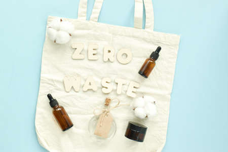 Zero waste on a cloth bag with glass bottles on a light blue background. Natural cosmetics. Flat...