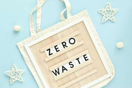 A sign with the inscription Zero waste on a fabric bag on a light blue background. Flat layout, top...
