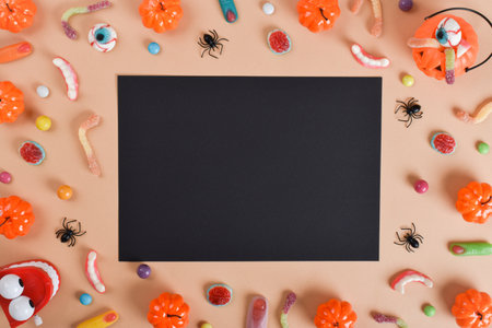 A black sheet next to various sweets on an orange background with a place for text. Happy Halloween. Flat layout, top view, a place to copy.の写真素材
