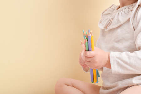 A little girl is holding pencils in her hands. Creative classes. Drawing for children. copy spaceの写真素材