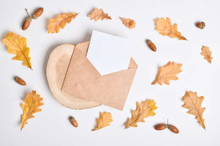 Invitation template with an envelope on a white background with autumn oak leaves and acorns. Autumn postcard. Flat layout, top view, a place to copy.の写真素材