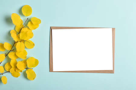 Invitation template with an envelope on a blue background with an autumn yellow branch. Romance. Flat layout, top view, a place to copy.の写真素材