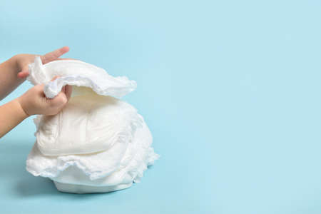 A stack of disposable panties on a blue background with childrens hands.の写真素材