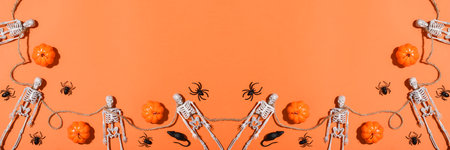 Halloween banner background with skeletons and pumpkins on an orange background. Flat layout, top view, a place to copy.の写真素材