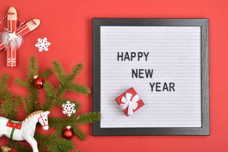Happy New Year and Christmas. A fir branch and Christmas decorations on a red background with a...