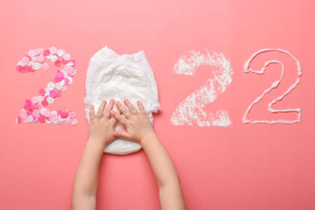 The numbers 2022 are lined with confetti, diaper, talcum powder and baby cream on a pink background. Themed Christmas card for the holiday. New Year and Christmas.の写真素材
