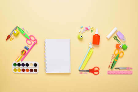 The numbers 2022 are laid out with stationery on a light yellow background. Themed Christmas card...