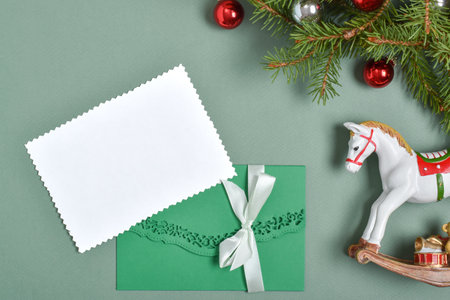 The layout of the invitation for Christmas, New Year. An empty postcard in a beautiful green envelope on a green background, with a fir branch. Copy space. Flat lay, top view.の写真素材
