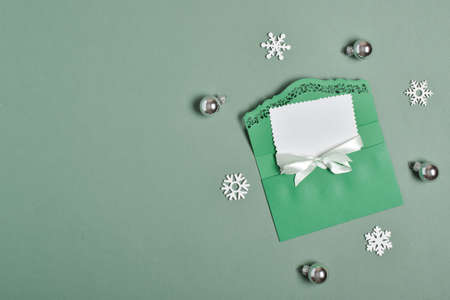 The layout of the invitation for Christmas, New Year. An empty postcard in a beautiful green envelope on a green background, with snowflakes and glass balls. A place to copy. Flat position, top view.の写真素材