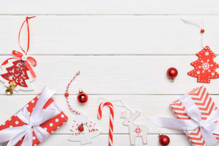 Festive background with a gift, candy cane and Christmas wooden toys on a white wooden table. Space...