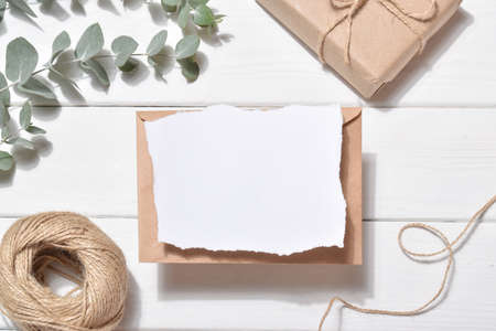 An empty invitation on a white background with eucalyptus branches and natural thread. Romance. Flat layout, top view, place to copy.の写真素材