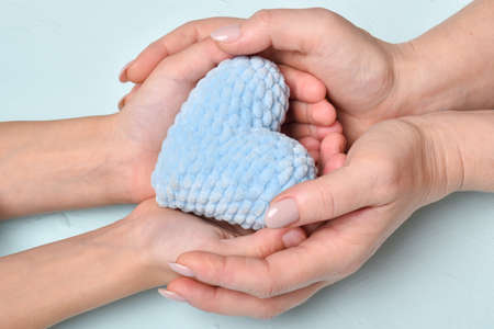 Adults and children's hands hold a blue heart. Healthcare, Love, Organization, World Health Day, Family Insurance, World Heart Day. Space for copying. A banner with a top view.の写真素材