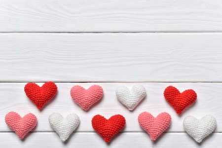 Three colored knitted hearts lie in 2 rows on a white background.