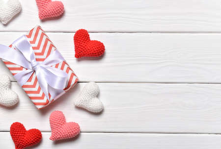 A banner for Valentines Day with knitted hearts in a row on the right side on a white wooden background. February 14.の写真素材