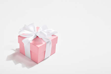 One pink gift with a white bow on a white background. Background for Valentine's Day. A postcard, a...