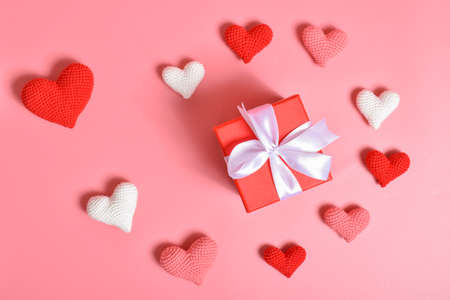 A gift surrounded by knitted hearts in the shape of a spiral.の写真素材