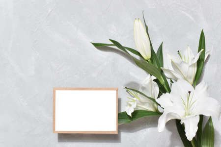 The template is a blank paper and an envelope with space for text on a gray background with lily flowers.の写真素材