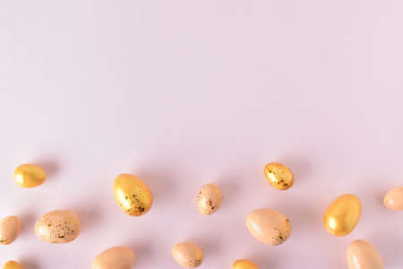 Various Easter eggs of yellow shades lie on a pink background. Easter background with painted eggs...