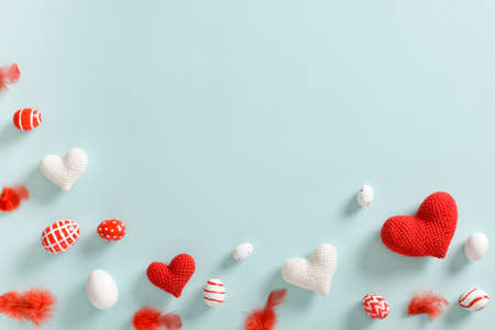 Card with red-and-white eggs with feathers and knitted hearts with a copy of the place for the text....