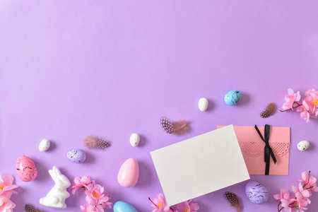 Kraft envelope on the background of Easter decor with eggs on a purple background. Invitation layout. A postcard for Easter. copyspace. Flat lay, top view.の写真素材