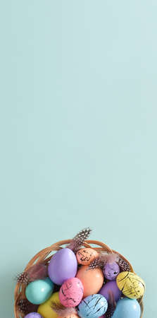 Vertical Easter banner. minimalism. A nest with painted Easter eggs and feathers. copyspace. Flat...