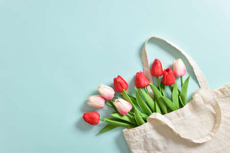 A beautiful bouquet of tulips in an eco bag on a light blue background. International Women's Day,...
