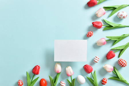 Background with tulips and Easter eggs with a blank sheet of paper.の写真素材