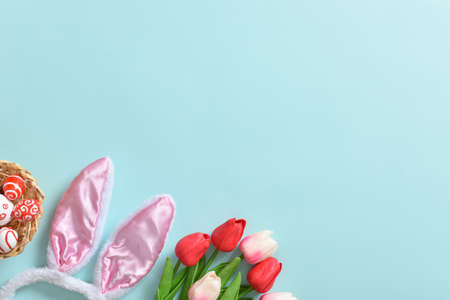 Background with rabbit ears, tulips and Easter eggs on a blue background. postcard, banner. happy...