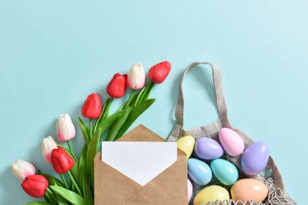 A beautiful bouquet of tulips with a string bag containing painted eggs. Banner for the Happy Easter...