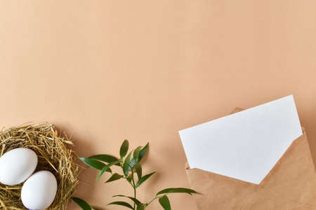 A mock-up of a kraft envelope with a white sheet of paper, eggs and a packed gift. Background for...