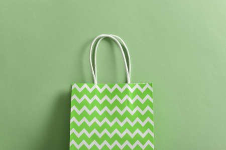 Green paper bag on a green background. Takeaway food delivery. Eco packaging. Zero waste. Flat layout, top view, place to copy. shopping and sales.の写真素材