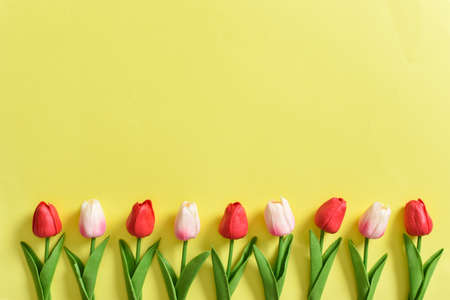 Invitation layout with tulips on a yellow background. copyspace. Flat lay, top view.の写真素材