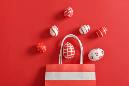 Red and white Easter eggs in a paper eco-bag, on a red background. Banner for a happy Easter holiday. Space for copying. Flat position, top view.の写真素材