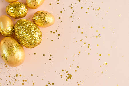 Close-up of Easter eggs with golden sequins on a beige background. Banner for a happy Easter holiday. Space for copying. Flat position, top view.の写真素材