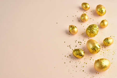 Easter eggs with golden sequins on a beige background. Banner for a happy Easter holiday. copyspace. Flat lay, top view.の写真素材