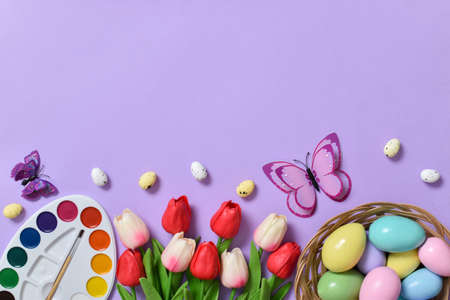 Easter background with painted eggs, colors and tulips and butterflies. Space for copying. Flat position, top view.の写真素材