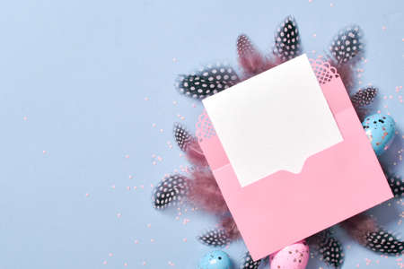 A mock-up of a pink envelope with a blank sheet of paper on a light blue background with Easter eggs...