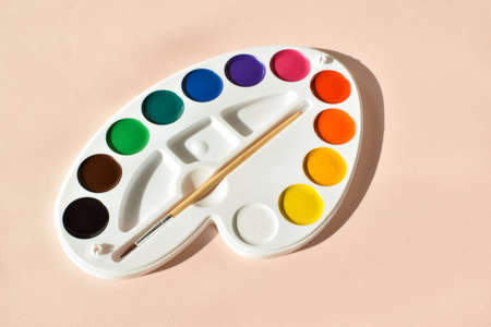 Watercolor paints in the form of an artistic palette on a beige backgroundの写真素材