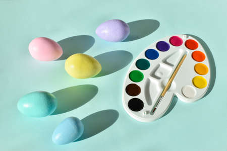 Paints and Easter painted eggs on a light blue background. Flat position, top view.の写真素材