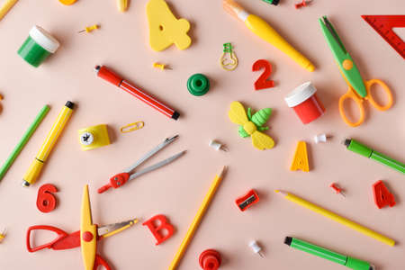 Various stationery of red, yellow and green colors are scattered on a beige background. back to school. A banner with office elements with space for text. Space for copying. Flat position, top view.の写真素材