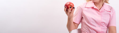 Banner beautician in pink uniform holding a big red apple. copyspace.の写真素材