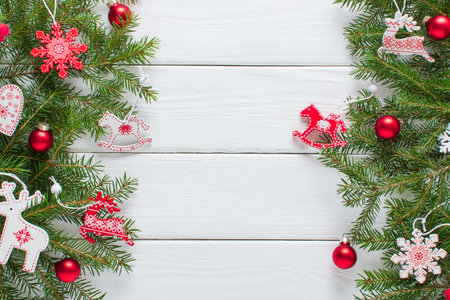 Christmas composition, frame with Christmas tree branches and red and white Christmas tree eco-toys on a white wooden background. Happy New Year and Merry Christmas. Space for copying. Flat position, top view.の写真素材
