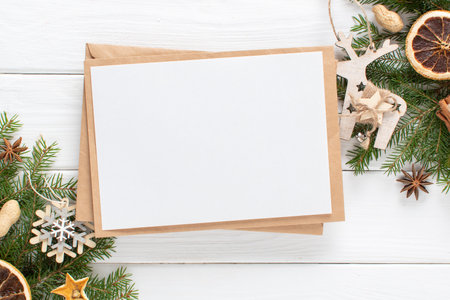 A mock-up of a Christmas invitation with branches of a Christmas tree and eco-natural decorations, orange, cinnamon on a white wooden background. copyspace. Flat lay, top view.の写真素材