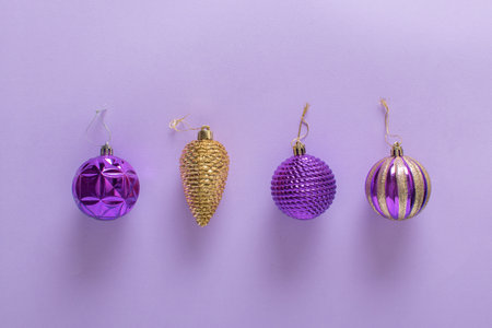Christmas composition with purple Christmas tree balls and a golden cone on a light purple background. Happy New Year and Merry Christmas. minimalism. Space for copying. Flat position, top view.の写真素材